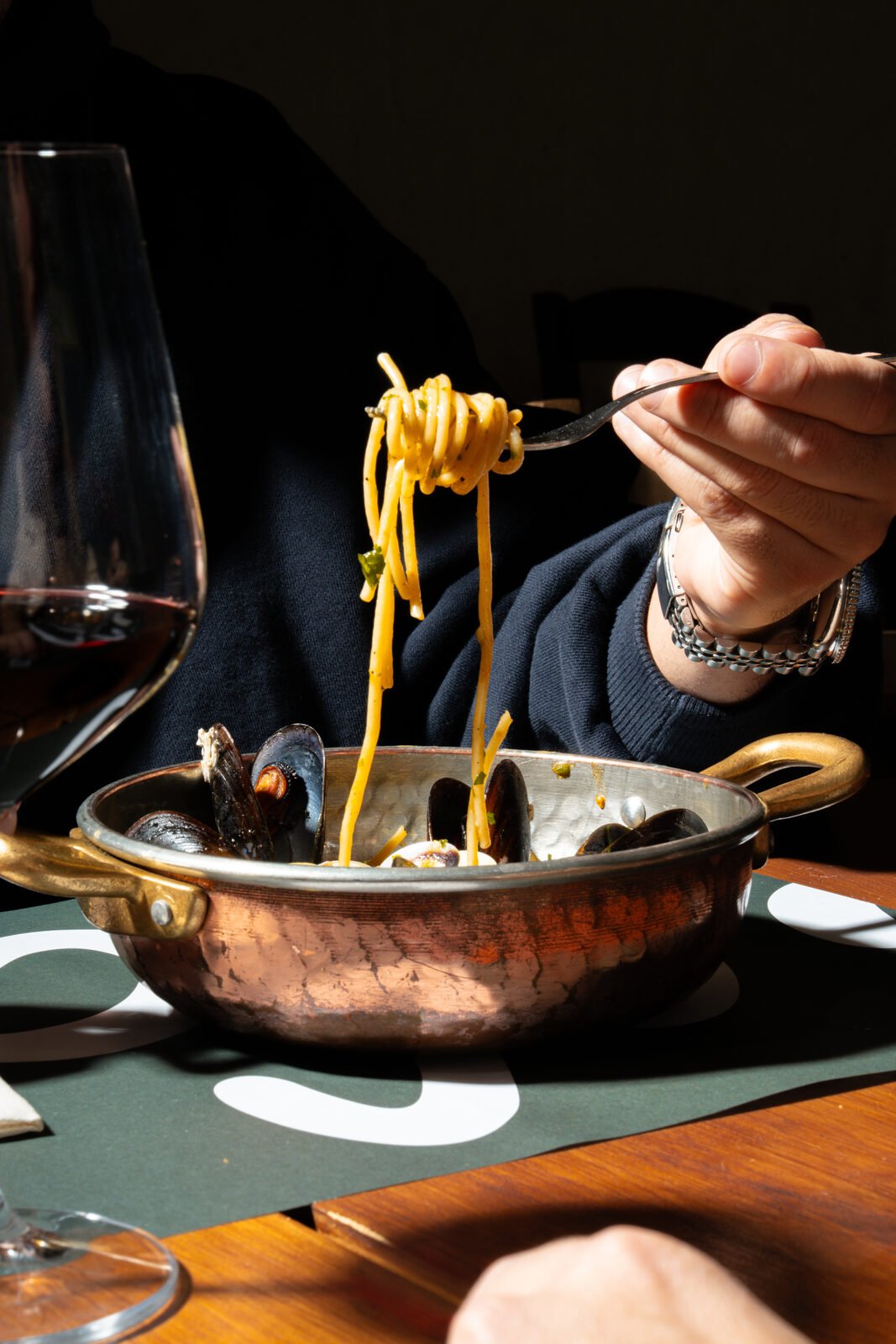 Spaghetti alle vongole servidos en cazuela de cobre con copa de vino — sesión editorial A'Napule