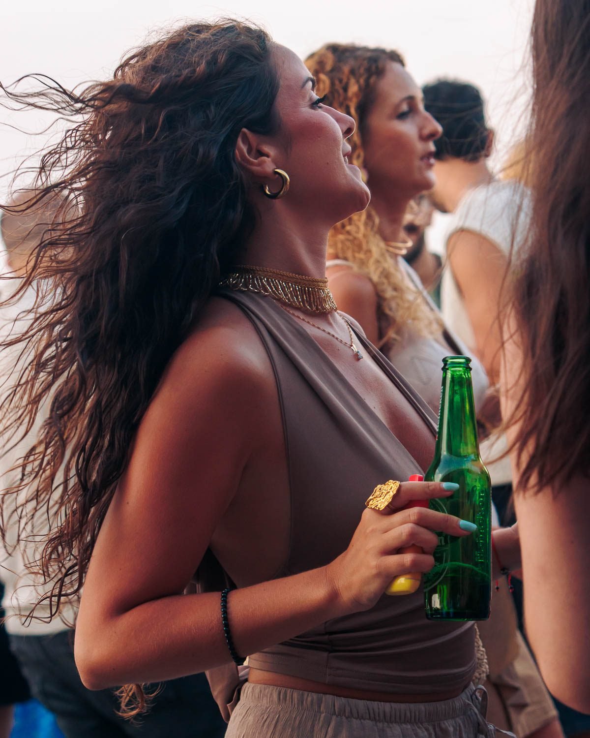 Mujer riendo durante la hora dorada en la terraza ÁTICO con cerveza en la mano