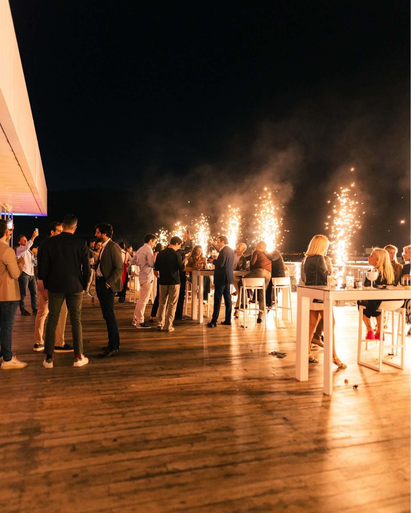 Terraza de ÁTICO de noche con bengalas encendidas y gente brindando