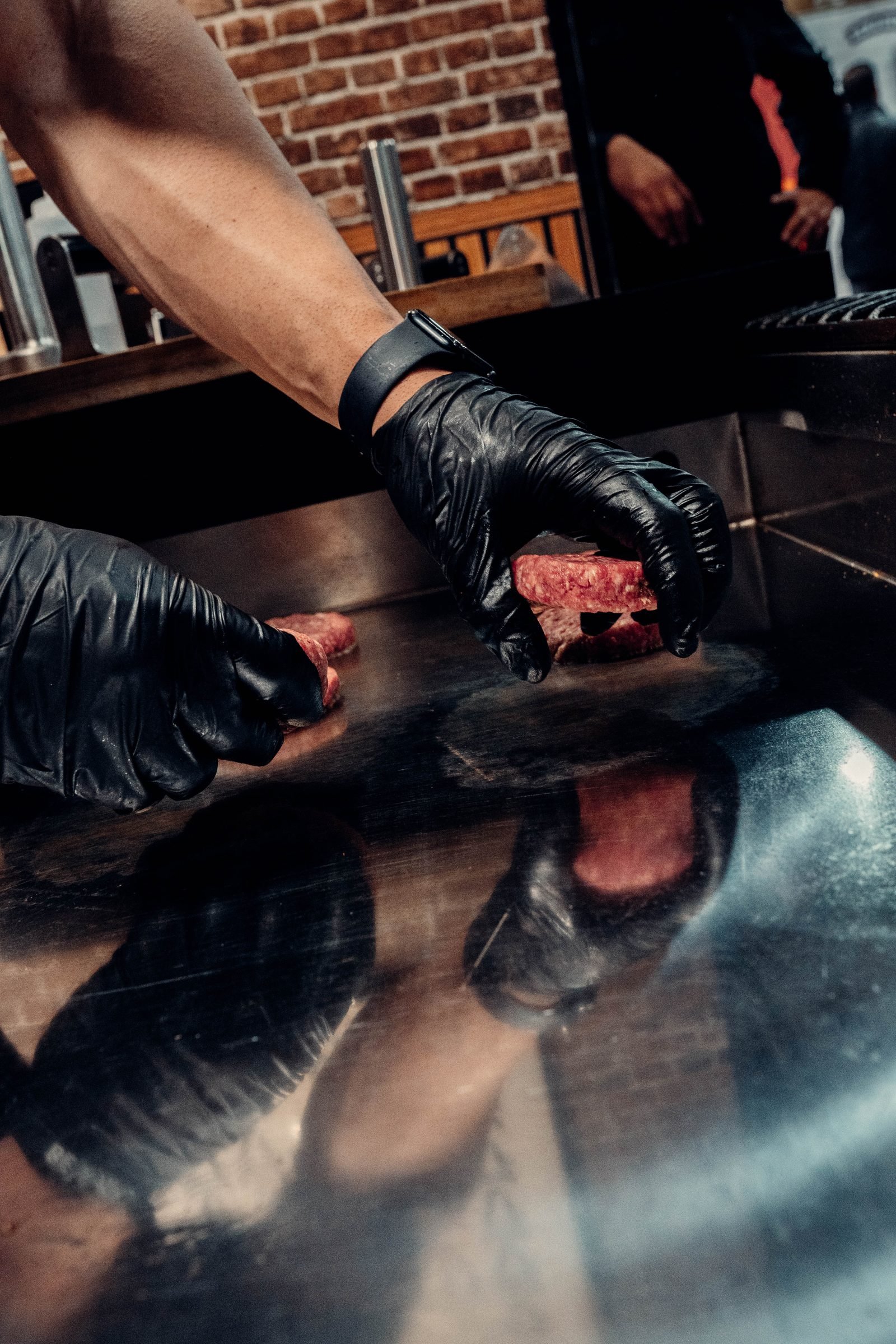 Cocineros con guantes negros preparando bolas de carne fresca sazonada sobre plancha de acero — CRUASH