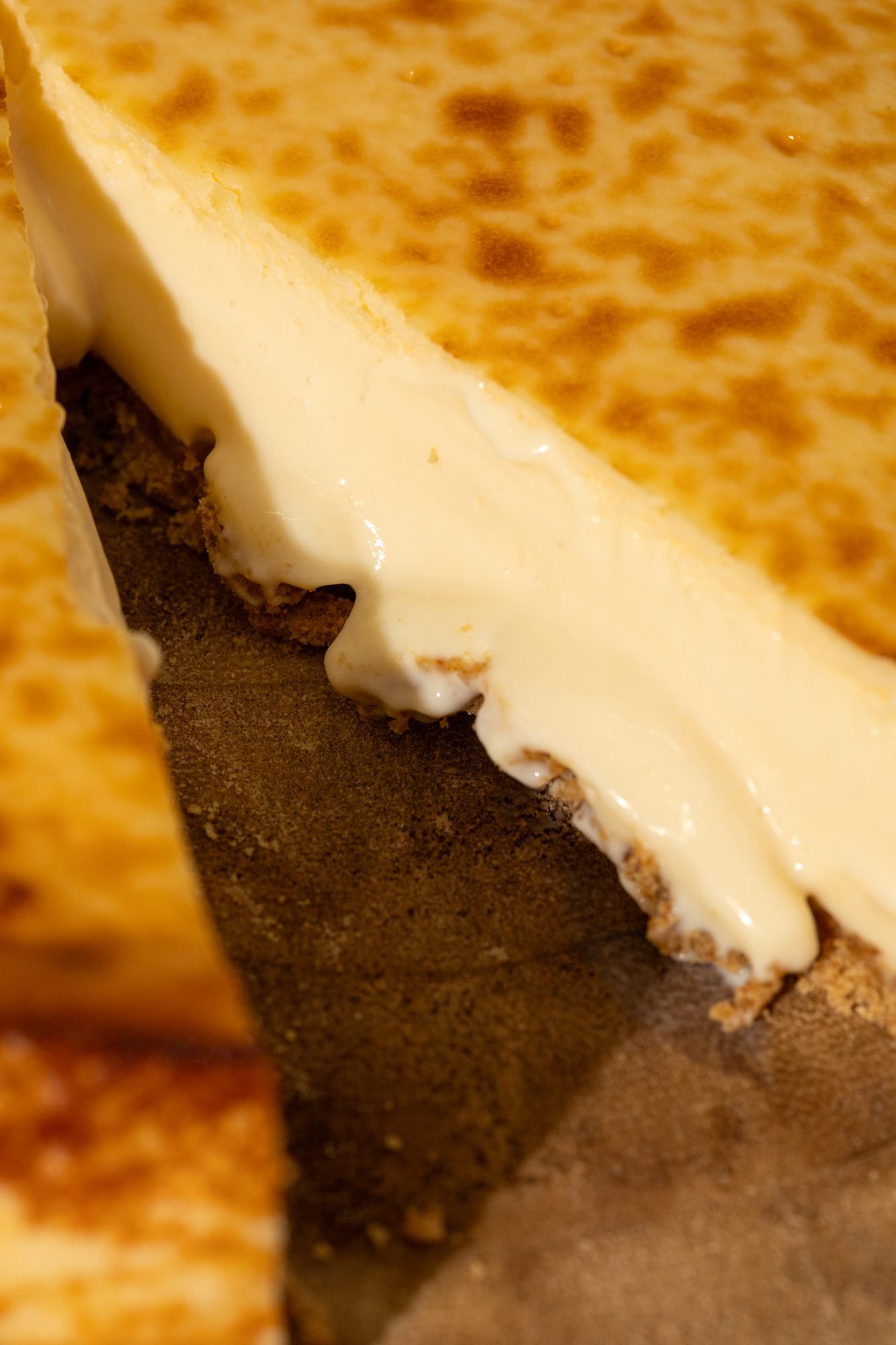 Porción de cheesecake de matcha levantada con espátula sobre fondo blanco — KÉIK