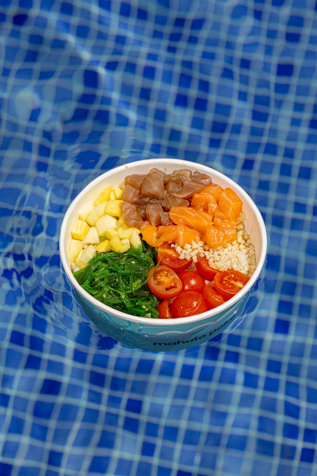 Bowl Mahalo flotando en una piscina de azulejos azules